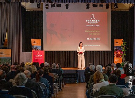 Frau steht auf Bühne vor Publikum bei Weintourismus Symposium am 21. April 2026 in Iphofen.